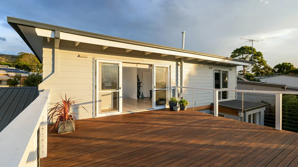 Wide view of a wood deck and sliding doors on a white house