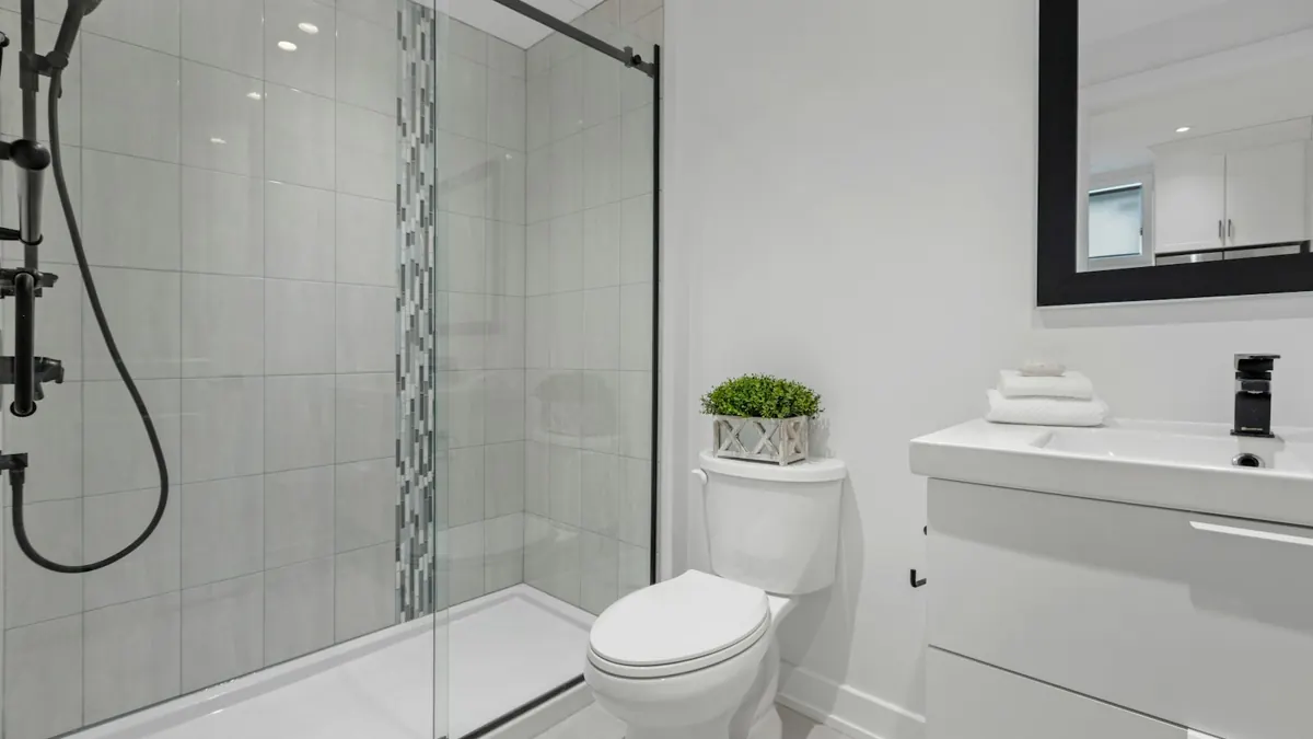Glass sliding shower door with gray tile wall